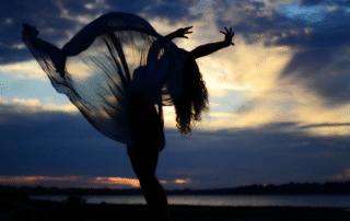 silhueta-de-una-mujer-bailando-en-la-orilla-del-mar-contra-el-cielo-al-anochecer