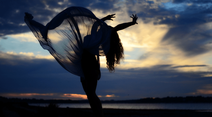 silhueta-de-una-mujer-bailando-en-la-orilla-del-mar-contra-el-cielo-al-anochecer